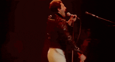 a man in a superman shirt is singing into a microphone .