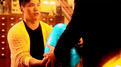 a man in a yellow cardigan is holding a blue ball in his hand .