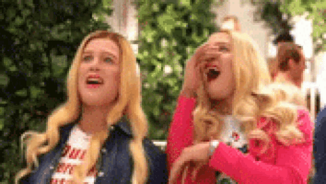 two women are standing next to each other and laughing .