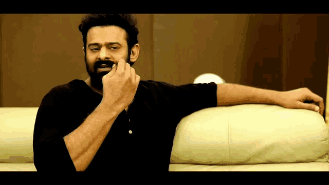 a man with a beard is sitting on a couch with his hand on his face