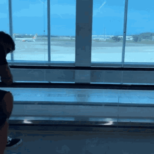 a person is looking out a window at an airport runway