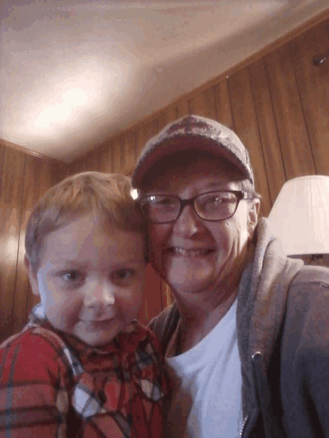 a woman wearing glasses and a baseball cap holds a child