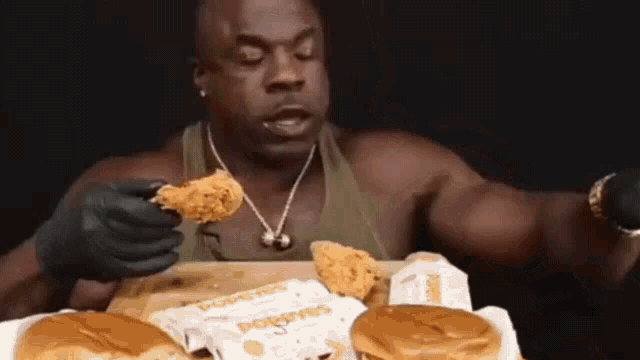 a muscular man is eating a chicken wing from a popeye 's bag