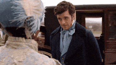 a man in a blue coat and tie talks to a woman