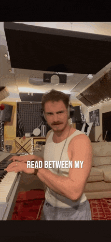 a man playing a piano with the words read between my on the bottom right