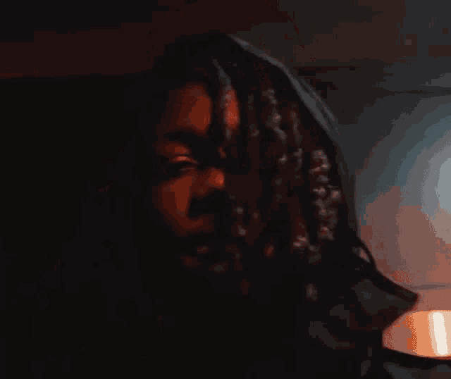 a close up of a person 's face in a dark room with a light behind them