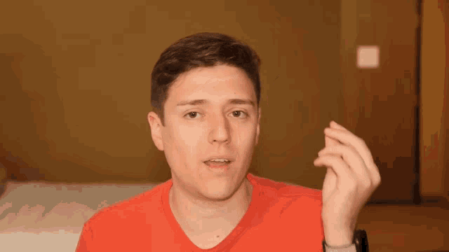 a young man in a red shirt is making a gesture with his hand