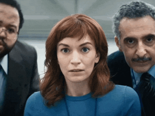 a woman in a blue sweater is surrounded by men in suits and ties