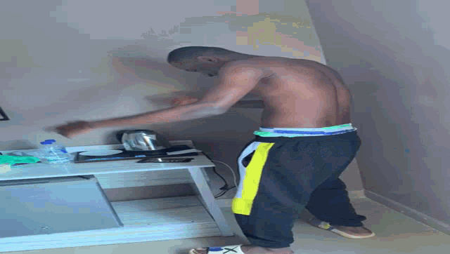 a man without a shirt is standing upside down in a kitchen