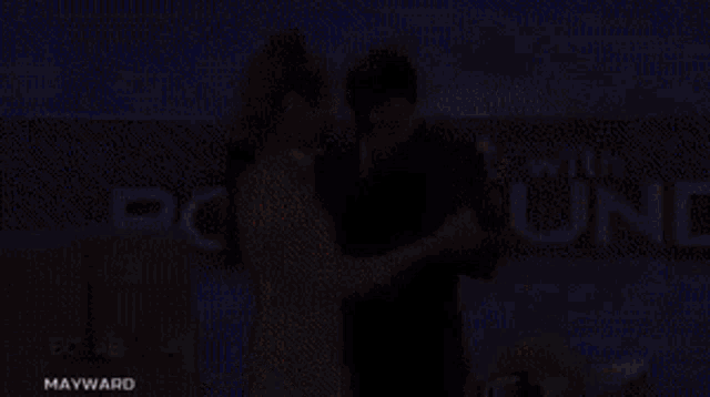 a man and a woman are dancing in front of a sign that says " with "