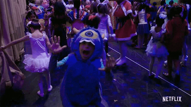 a group of children are dressed up in costumes and dancing in a room with a netflix logo in the corner .