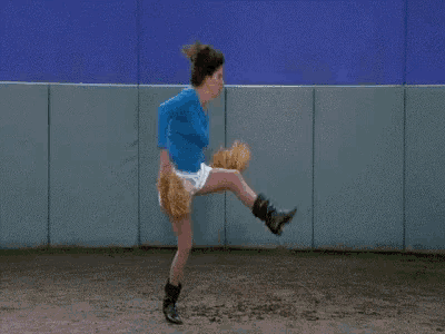 a woman in a blue shirt is throwing a baseball