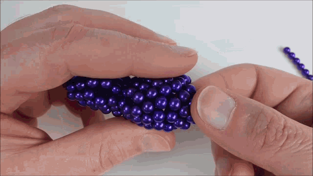 a person is holding a bunch of blue beads in their hands