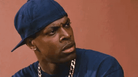 a man wearing a blue hat and a chain around his neck is making a face .