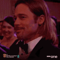 a man in a tuxedo is applauding with a heart behind him