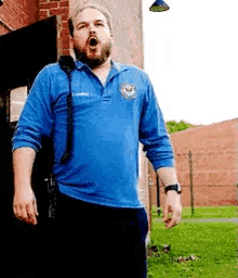 a man with a beard is wearing a blue shirt and talking on a phone