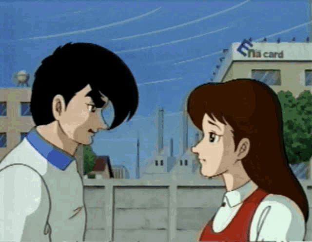 a man and a woman are looking at each other in front of a building with the word na card on it