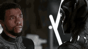 a man and a black panther are standing next to each other .