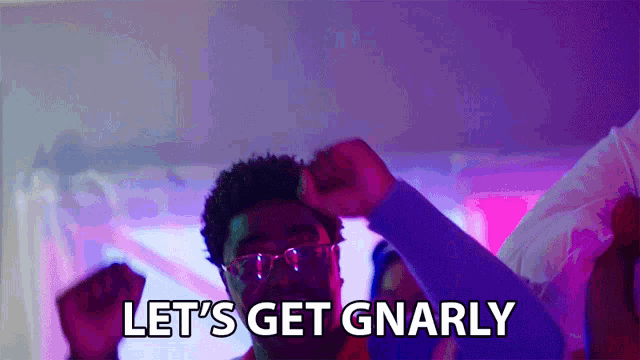 a man in glasses says let 's get gnarly while raising his fist in the air