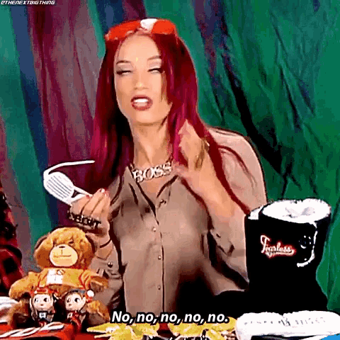 a woman with red hair and a necklace that says boss is sitting at a table with a teddy bear and popcorn .
