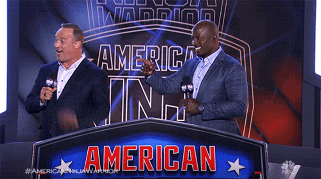 two men standing behind a sign that says american