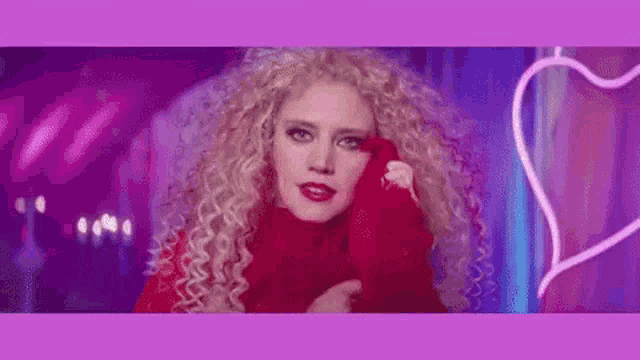 a woman with curly hair is wearing a red sweater and a red sweater .