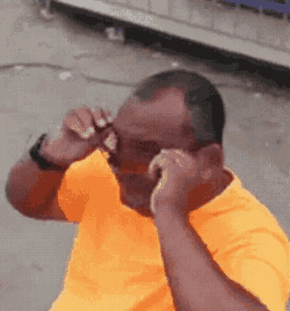 a man in an orange shirt is talking on a cellphone