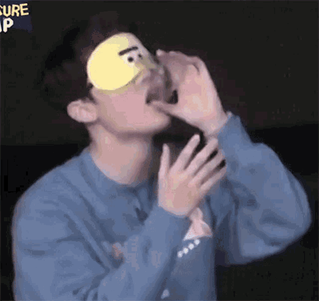 a young man wearing a sleep mask with a face on it is licking his lips .