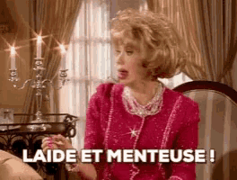 a woman in a pink dress is sitting on a couch and says laide et menteuse