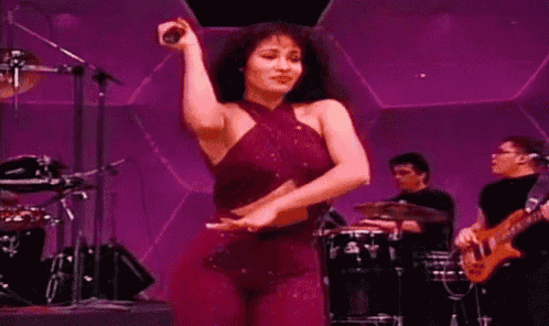 a woman in a red dress is singing into a microphone while dancing on stage .