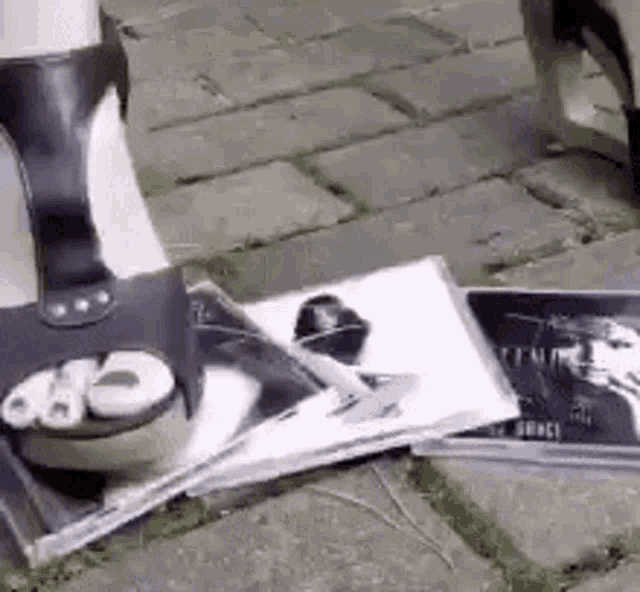 a woman 's foot is standing on a stack of magazines on the ground .