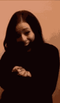 a woman in a black top is smiling and holding her hands out