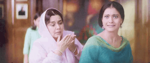 two women are standing next to each other in a room and one of them is holding the other 's hand .