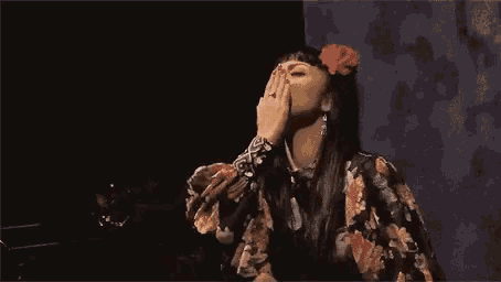 a woman in a floral dress covering her face with her hand