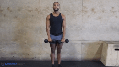 a man in a black tank top is holding a pair of dumbbells .