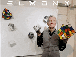 an elderly man holding a rubik 's cube in front of a white board that says elmon x