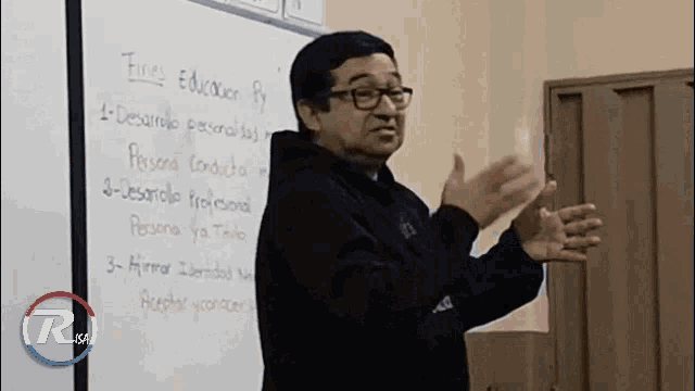a man stands in front of a white board that says educacion