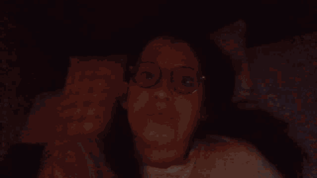 a woman wearing glasses is laying in bed
