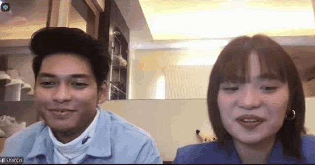 a man and a woman are sitting next to each other on a video call and the man is wearing a blue jacket