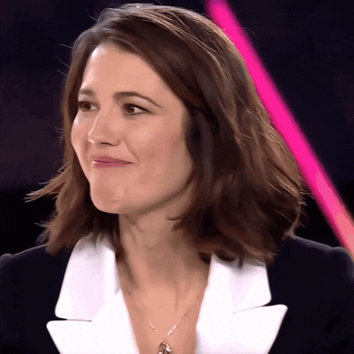 a close up of a woman 's face with a pink light in the background