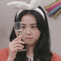 a woman with bunny ears is holding a glass of wine .