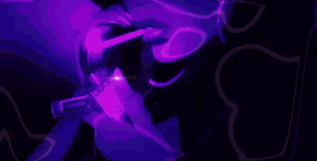 a person is holding a purple object in their hand in the dark .