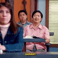 a group of people are sitting in a room and one of them is saying gaaaay !