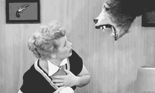 a woman is standing next to a stuffed wolf with its mouth open .