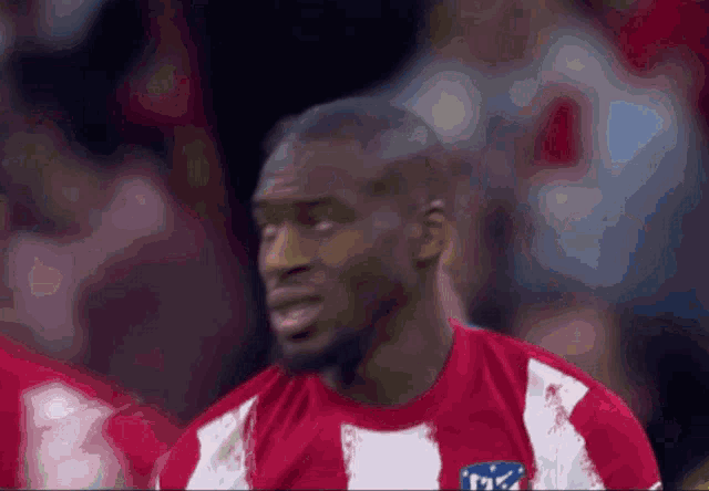 a man wearing a red and white striped shirt with the letter m on the front