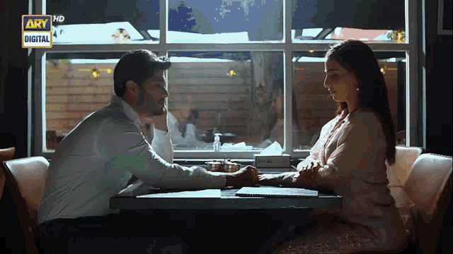 a man and a woman are sitting at a table in front of a window with the words ary digital on the bottom
