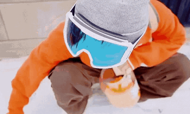 a person wearing ski goggles and a beanie is kneeling down in the snow