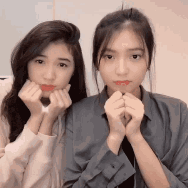 two girls are posing for a picture and one has her hands on her face