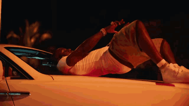 a man laying on top of a white car
