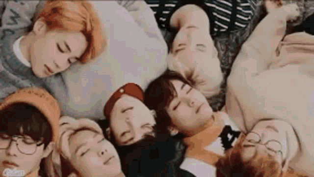 a group of young men are laying in a circle on the floor with their heads together .